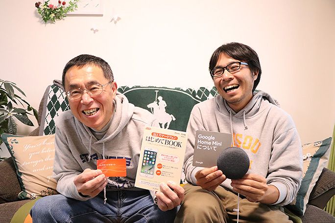 Google Home Mini と「はじめてBOOK」、会員カードを手に笑顔の地主親子