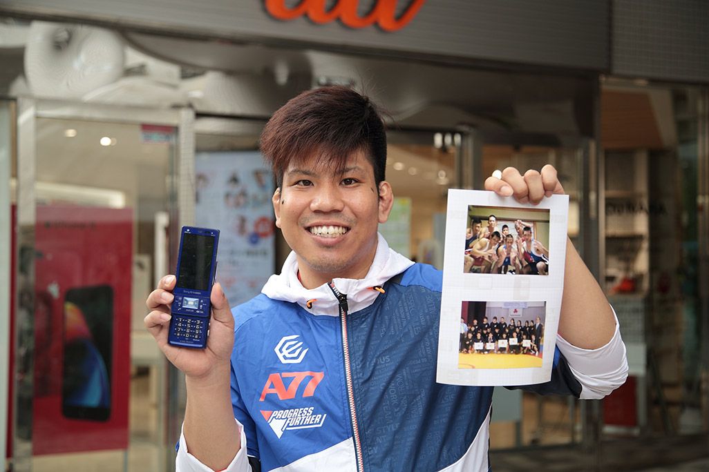 auおもいでケータイ再起動でプリントアウトした写真と共に微笑む男性