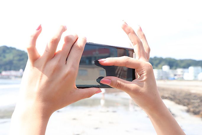 インスタ映えの風景を拡大する女性の手