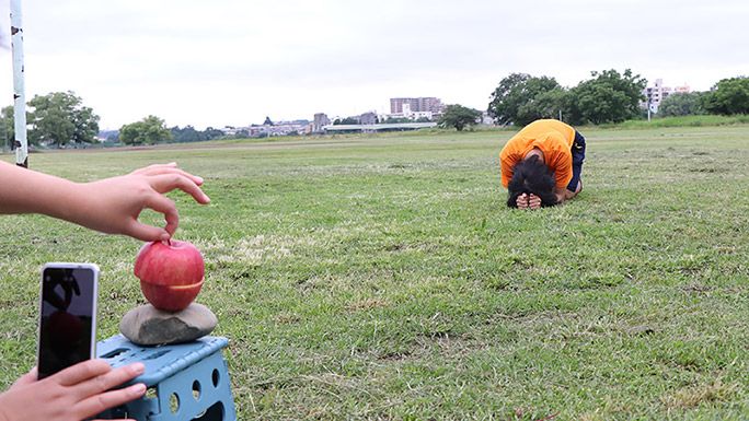 遠近法でリンゴに隠れるように小さくなるライターの地主