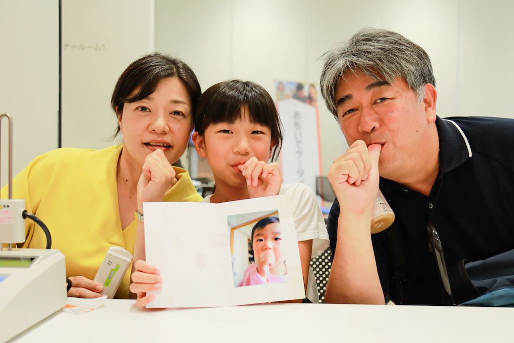 おもいでケータイ再起動でプリントした写真を手にポーズをとるご家族