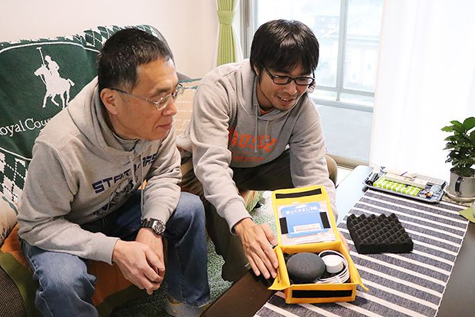 リビングにて Google Home を開封する地主と父