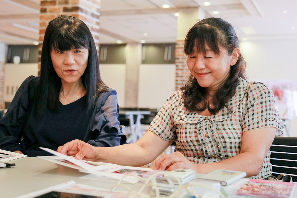 「おもいでケータイ再起動」の会場でプリントアウトした写真を見ながら微笑む参加者