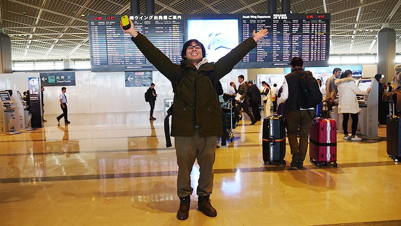 空港の出発ロビーで TORQUE G03を持ち両手を広げる地主