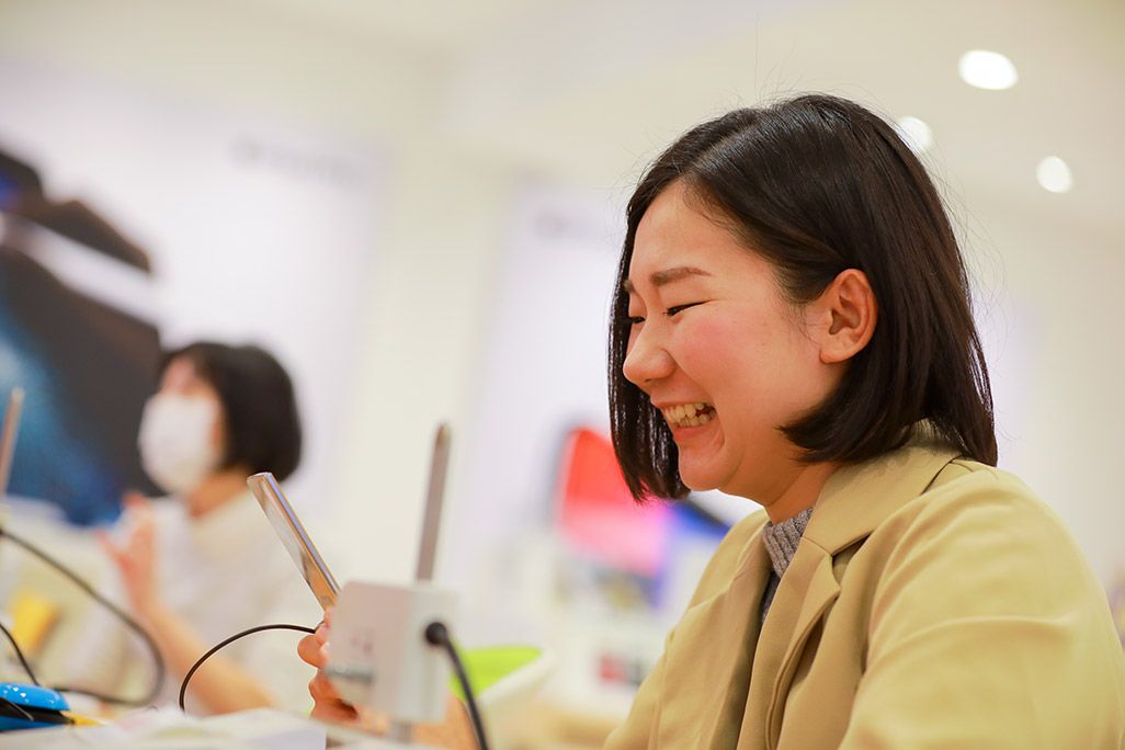 au 昔、使っていたケータイを見つめて笑う女性
