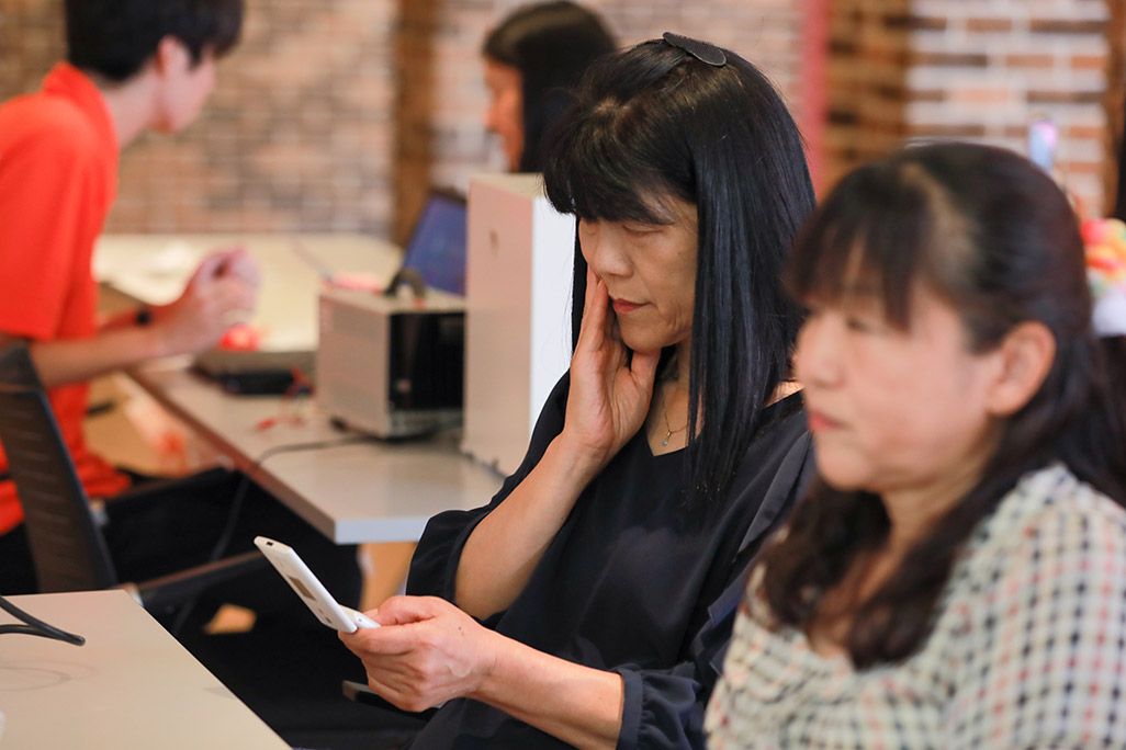 「おもいでケータイ再起動」で復活したケータイのディスプレイを見る女性