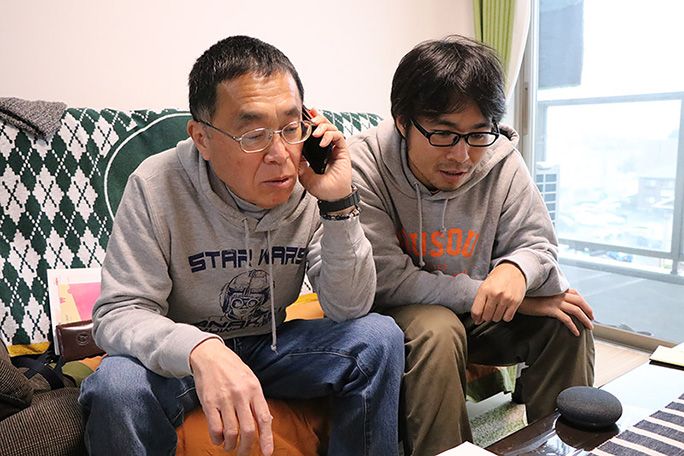 auスマートサポートに電話する父と横に寄り添う地主
