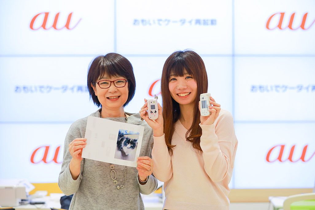 再起動したケータイからお気に入りの1枚をプリントアウトして微笑む母娘