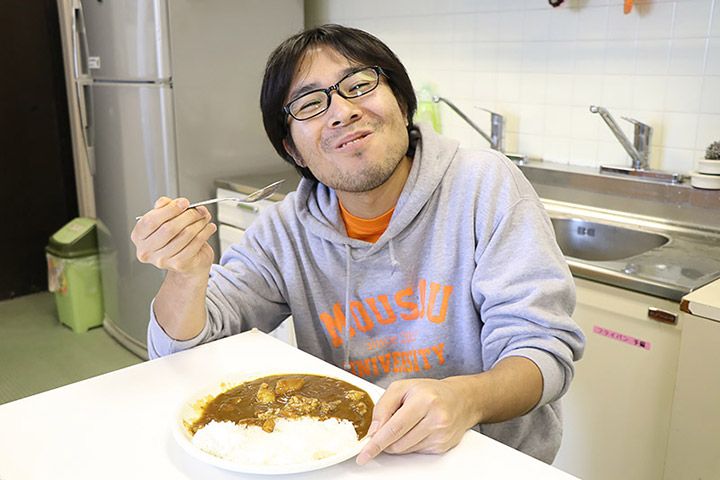 笑顔でカレーを食べるライターの地主