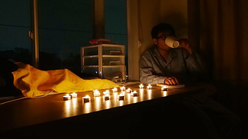 ろうそくの光の中、白湯を飲む地主