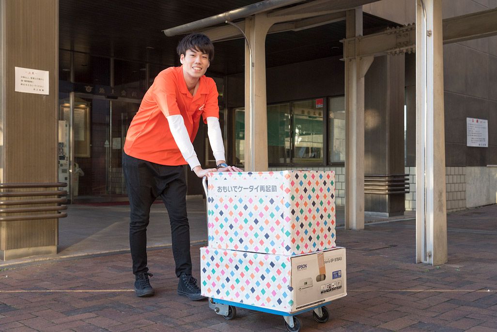 機材を手に古いケータイの再起動に赴くKDDIスタッフ