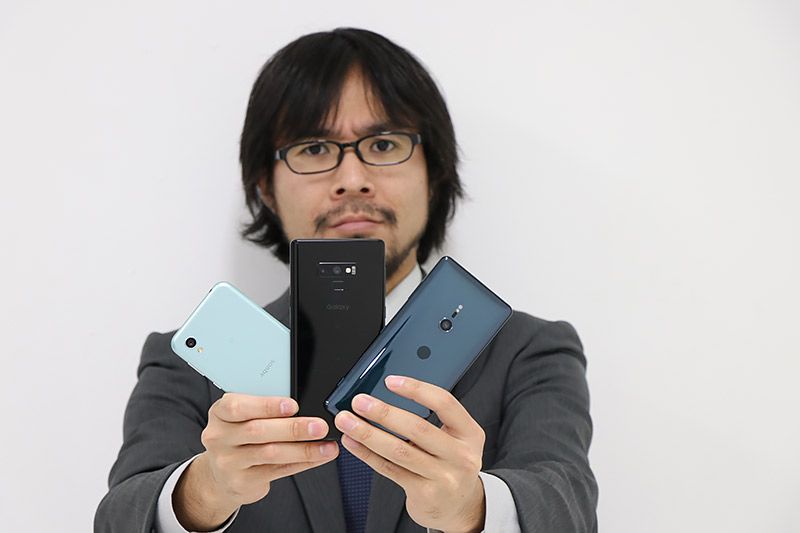 3つのスマートフォンを持ってこちらに見せてくる地主