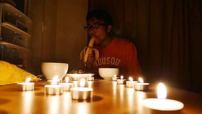 ろうそくだらけの部屋でバナナを食べる地主