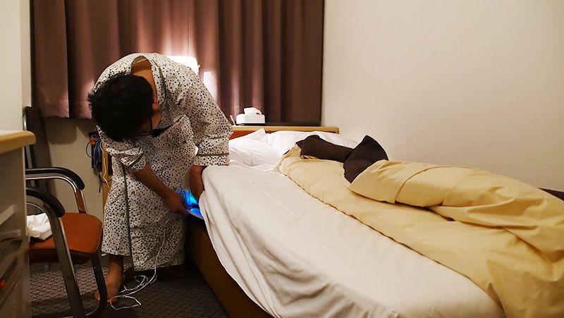 ホテルのマットレスの下に睡眠モニター 01をセッティングする地主