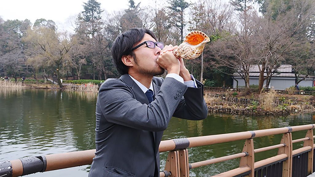 水辺で法螺貝を吹く地主