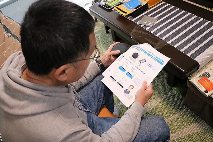 説明書を片手に、 Google Home Mini を持つ父