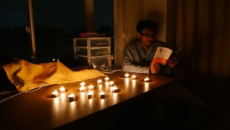 ろうそくだらけの部屋で自著を読む地主
