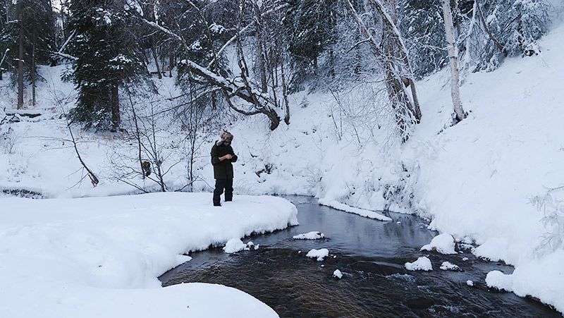 雪原の中に流れる川を眺める地主