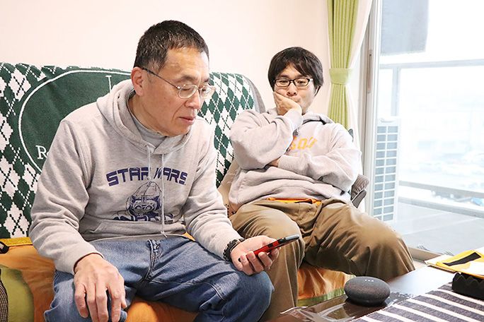 Google Home Mini を設定する父とヒマそうに眺める地主
