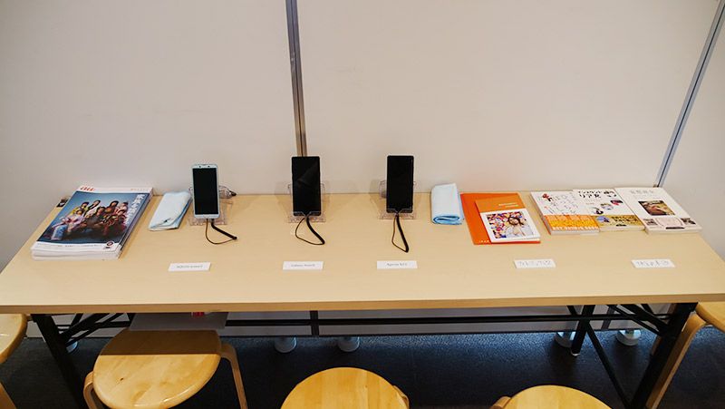 写真展にて展示されたスマートフォン、フォトブック、書籍など